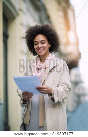 Young mixed raced woman holding documentation outdoor