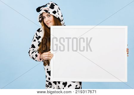Smiling teenage girl in funny nightclothes pajamas cartoon style with blank empty banner board. Advertisement copyspace.