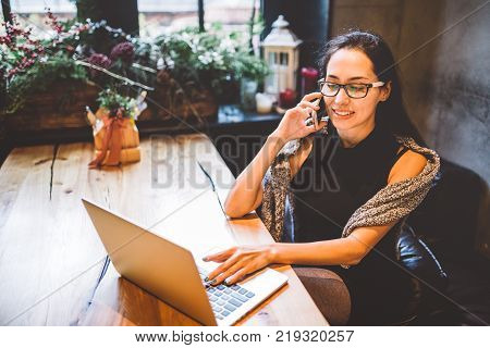 Beautiful Young Brunette Woman Inside Cafe With Christmas Interior At Wooden Table By The Window Tal