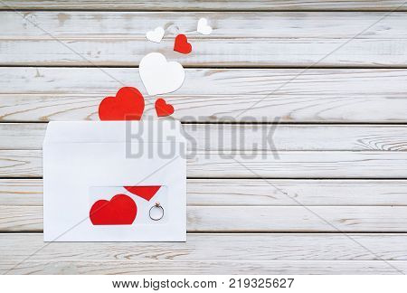 Wedding ring for St. Valentine's Day. The offer to get married. A gift for St. Valentine's Day. Envelope with a ring on a wooden background. Copy space. Marriage propose.