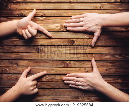 The girl's fingers points to an empty spot intended for advertising. Wooden background. Copy space.