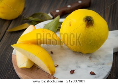 Sliced yellow quince or queen apple autumn fruits with seeds on marble cooking board close-up