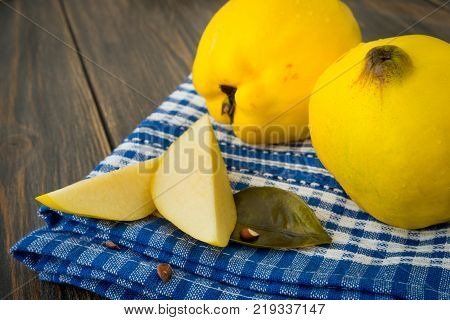 Sliced yellow quince or queen apple fruits with seeds on blue checkered towel close-up