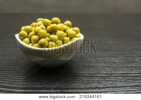 Green peas in a white bowl on the table.