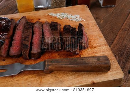 fresh roast red beef meat fillet mignon cutted on wooden plate with many different kinds of dry spices red hot paprika crushed black pepper salt dry mustard grains over table
