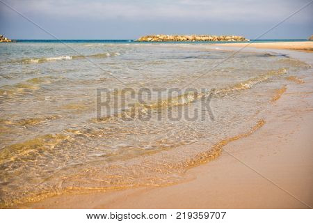 Background. A close-up of a wave runs over a sandy beach