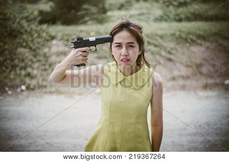 Stressed woman with holding gun on hand point to her head.She is saddened by the disappointment in love. concept of broken heart, heartbroken, lovelorn, Suicide.