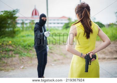 Criminal or Bandit wear black mask use knife point to woman trying to rob money and hurting her but the woman but women hid their guns behin concept of winner fighting usurpation