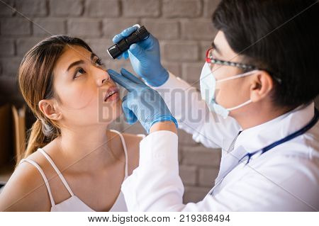 The doctor wear white coat shines a flashlight to the patient's eyes at the clinic. Concept of Healthcare Medical treatment examination
