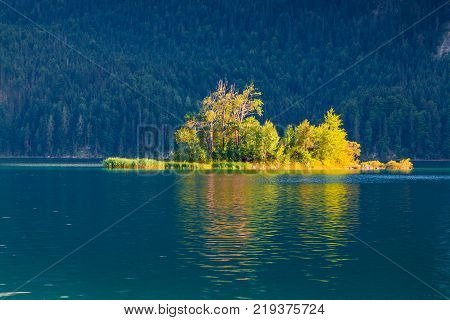 Colorful islang glowing by sunlight on the Eibsee lake. Splendid outdoor scene in German Alps Bavaria Garmisch-Partenkirchen village location Germany Europe. Artistic style post processed photo.