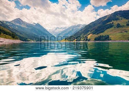 Reflection of the of Richterspitze mountain range in the pure water of Speicher Durlassboden lake. Schwaz district in the Tyrol state of Austria Europe. Artistic style post processed photo.