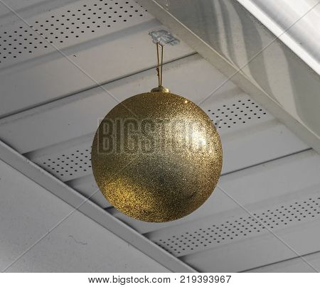 A lclose up of a large gold Christmas Ball hanging from a house as decoration for the holidays.