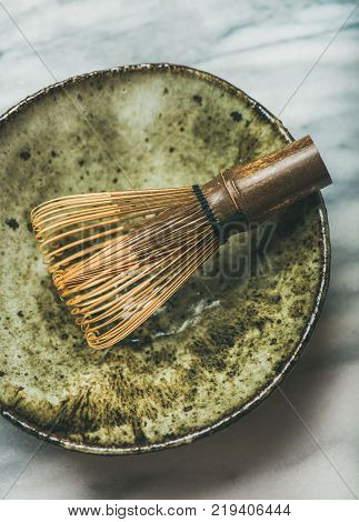 Flat-lay of Japanese tools for brewing matcha tea. Chasen bamboo whisk, Chawan bowl over grey background, top view