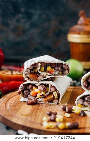 Nice vegetarian burrito over black table on wooden board