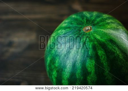 Close-up view of whole undivided watermelon. Green fresh watermelon on brown wooden background