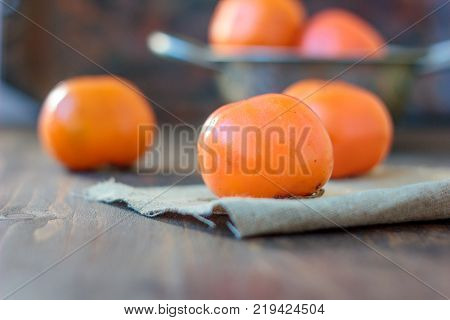 Group of persimmons on wooden table and piece of fabric