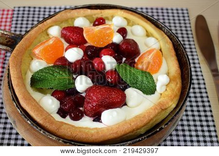 Danish pancake with berries and whipped cream topping covered with sugar powder