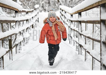 Little Cheerful Boy Runs In Winter On Bridge.
