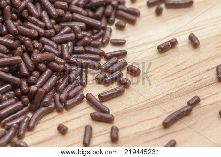 close up of pile chocolate sprinkles on wooden plate