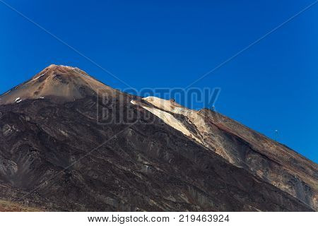 An uphill view of the colourful Teide volcano in Teide National Park, Tenerife, Canary Islands. Pictured in the distance is a cablecar leading up to the 3718 m Teide peak, the tallest peak in Spain.