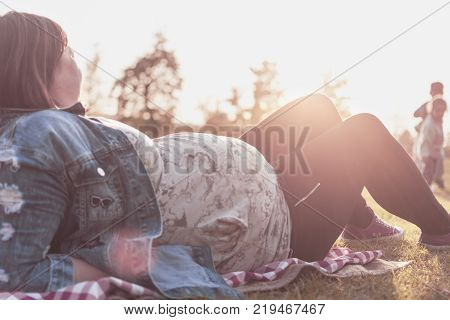 a pregnant woman with two children enjoying and watching her children play