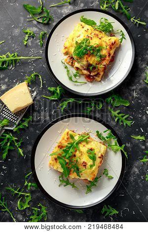 Homemade lasagna with minced beef bolognese and bechamel sauce topped wild arugula, parmesan cheese.
