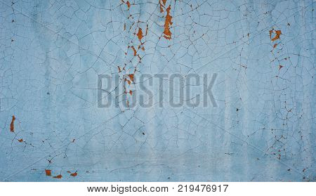 Wooden wall with blue paint is severely weathered and peeling. close up