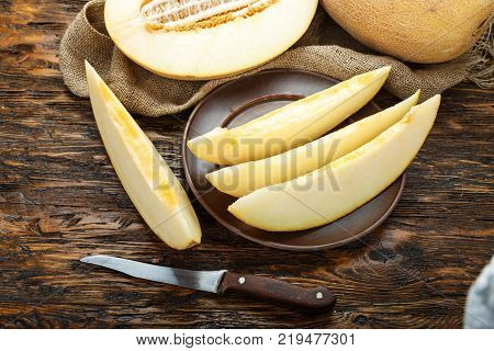 fresh juicy ripe melon cut into slices on next to it is half a melon