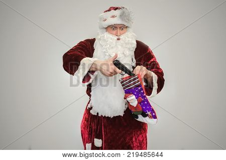 Bad angry Santa Claus with guns in hands isolated on gray background.