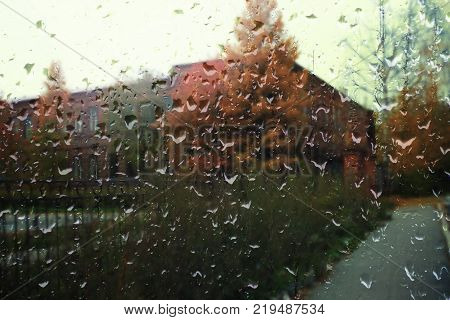 Autumn street on a rainy day view through wet glass