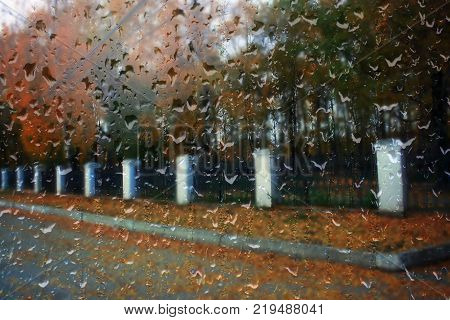 Autumn street on a rainy day view through wet glass
