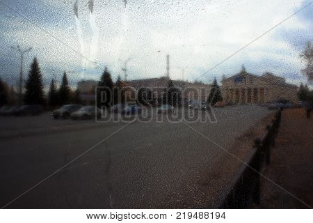 Autumn street on a rainy day view through wet glass
