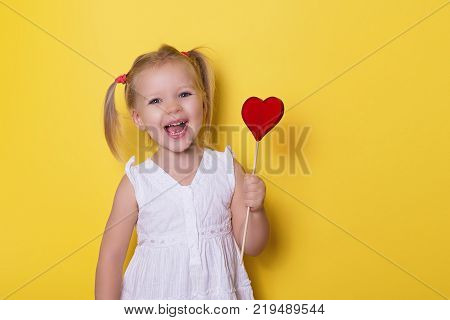 Pretty girl with red bright lollipop candy on yellow background valentines day holiday love theme