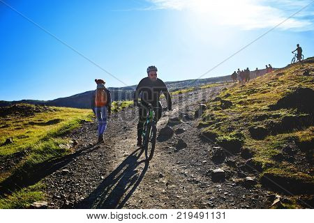 back view of woman traveler on a walk in the Valley of the river of Hveragerdi Iceland, the cyclist bikes down the slope. Hiking Tour of Reykjadalur Hot Springs