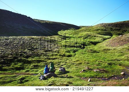 couple hikers having rest on the trail in Valley of the river of Hveragerdi Iceland. Hiking Tour of Reykjadalur Hot Springs