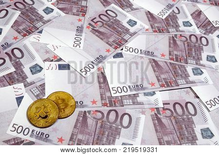 Bitcoins over pile of five hundred euro banknotes. Traditional money versus cryptocurrency concept. Gold coin above 500 euro bills. Close up