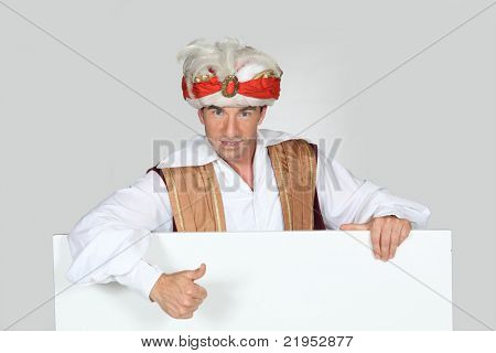 Uomo in un turbante di costume dà il pollice fino a un vuoto di sinistra di bordo per la vostra immagine