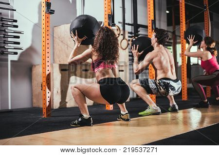 fitness, sport and exercising concept - group of people with medicine balls training in gym