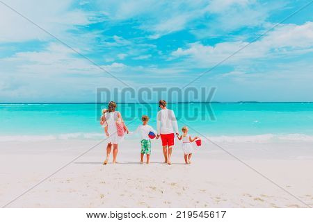happy family with three kids walk on tropical beach