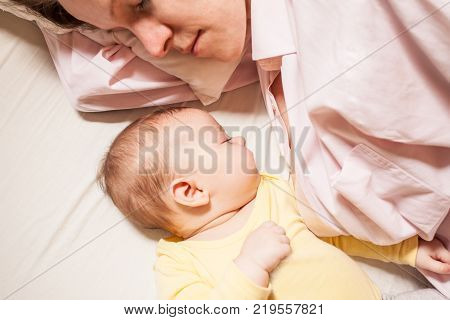 co-sleeping mother and three months baby after breastfeeding on the bed