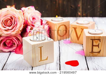 Valentines day oncept: burning candles and word Love made of wooden candle holders. Copy space