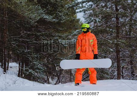 Snowboarder with the white snowboard posing in winter forest