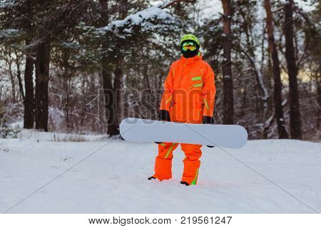 Snowboarder with the white snowboard posing in winter forest