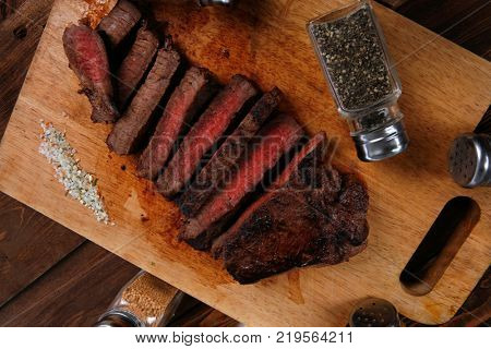 fresh roast red beef meat fillet mignon cutted on wooden plate with many different kinds of dry spices red hot paprika crushed black pepper salt dry mustard grains over table