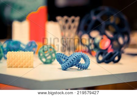Many abstract models bright colorful objects printed on a 3d printer on a white table. Fused deposition modeling, FDM. Progressive modern additive technology. Concept of 4.0 industrial revolution