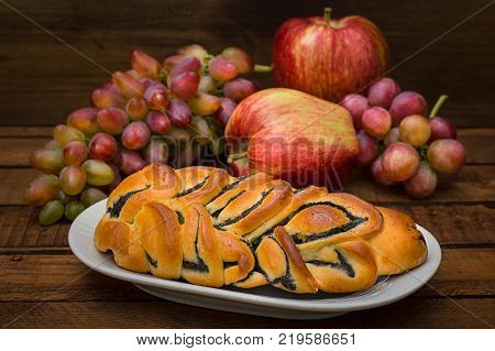 Still life of homemade pastries, sweet poppy pie on the background of fresh fruits, apples and grapes. Top View. Wooden rustic background
