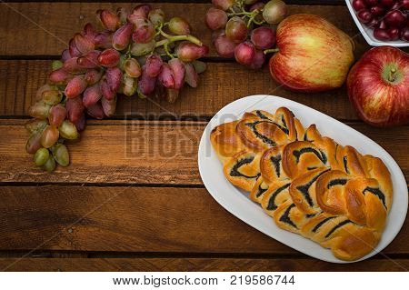 Still life of homemade pastries, sweet poppy pie on the background of fresh fruits, apples and grapes. Top View. Wooden rustic background