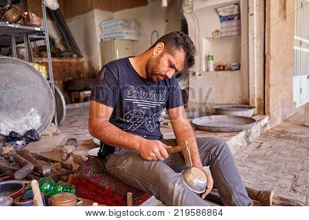 Yazd Iran - April 22 2017: A young tinsmith leveling the bowl using a tool similar to a hammer.