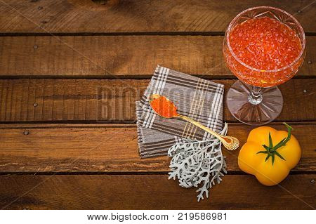 Red caviar in glass jar with gold spoon close up. Sea food. Healthy eating. Diet. Wooden rustic background. Top view. Selective focus