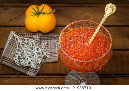 Red caviar in glass jar with gold spoon close up. Sea food. Healthy eating. Diet. Wooden rustic background. Top view. Selective focus